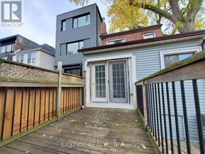 Toronto (Danforth) apartment for rent - A wooden deck leads to a grey house with a glass door.