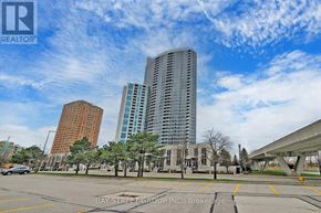 Toronto (Bendale) condo for rent - A city street with a large building in the background and a parking lot in the foreground.