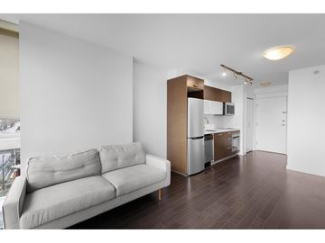 Surrey apartment for rent - A modern living room with a grey couch and a kitchen area in the background.