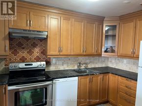 Toronto (Flemingdon Park) condo for rent - A kitchen with wooden cabinets and a black countertop.