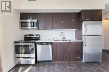 Toronto (Mimico) condo for rent - A kitchen with dark wood cabinets and stainless steel appliances.