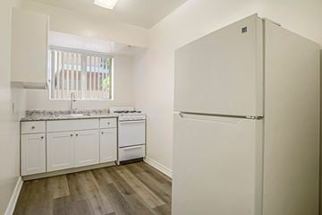 Glendale apartment for rent - A white refrigerator stands in a kitchen with wooden floors and white cabinets.