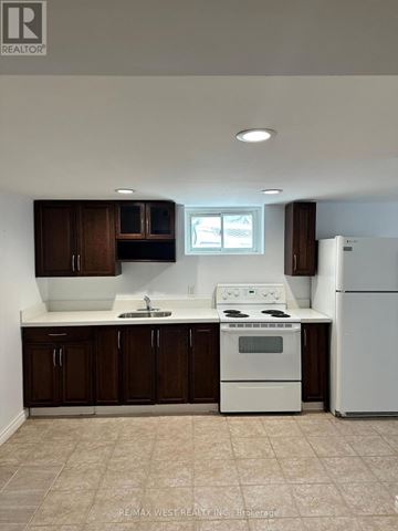 Toronto (Highland Creek) apartment for rent - A white stove and refrigerator in a kitchen with brown cabinets.