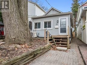 Toronto (Oakridge) apartment for rent - A house with a grey siding and a white door is surrounded by a wooden fence and a tree.