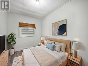 Toronto (Oakridge) apartment for rent - A bedroom with a large bed, a potted plant, and a painting on the wall.