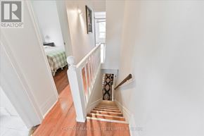 Toronto (Roncesvalles) townhouse for rent - A staircase with a wooden floor and white railings leads to a bedroom.