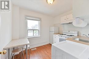 Toronto (Roncesvalles) townhouse for rent - A small white kitchen with a table and chairs.