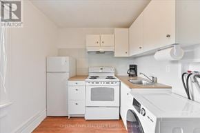 Toronto (Roncesvalles) townhouse for rent - A white kitchen with a refrigerator, stove, and sink.
