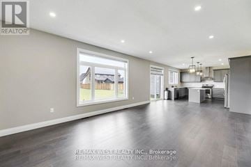 Thames Centre apartment for rent - A spacious living room with a large window and a kitchen area in the background.
