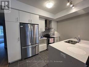 Guelph (Kortright East) townhouse for rent - A modern kitchen with a stainless steel refrigerator and a white countertop.