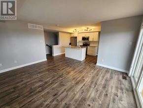Ottawa condo for rent - A spacious room with wooden flooring and a kitchen area in the background.