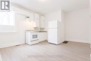 Toronto (East York) apartment for rent - A white kitchen with EXP REALTY, Brokerage written on the floor.