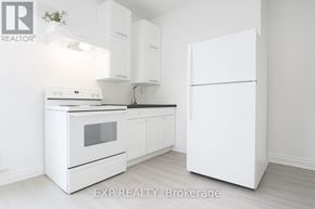 Toronto (East York) apartment for rent - A white kitchen with a refrigerator, oven, and sink.