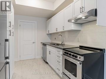 Toronto (Rustic) townhouse for rent - A kitchen with white cabinets and a black stove top oven.