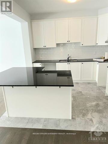Ottawa townhouse for rent - A kitchen with white cabinets and a black countertop.