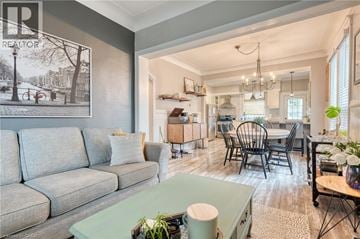 Hamilton apartment for rent - A living room with a grey couch and a dining area with a table and chairs.