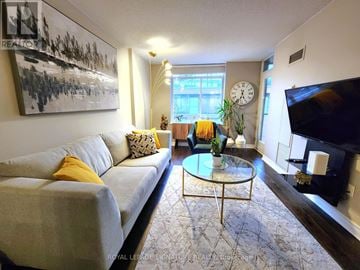 Toronto (Waterfront Communities) condo for rent - A living room with a grey couch, a glass coffee table, and a painting on the wall.
