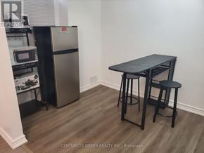 Whitby (Pringle Creek) apartment for rent - A kitchen area with a table, two stools and a fridge.