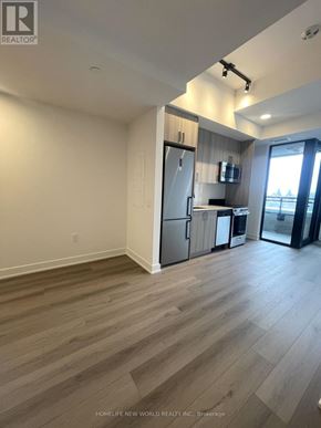 Toronto (Dovercourt-Wallace Emerson-Junction) condo for rent - A spacious room with wooden flooring and a kitchen area with a refrigerator, microwave, and oven.