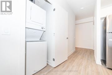 Ottawa condo for rent - A white refrigerator is in a kitchen with wood floors and white walls.