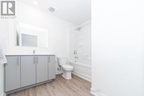 Ottawa condo for rent - A white bathroom with a toilet, sink, and cabinet.