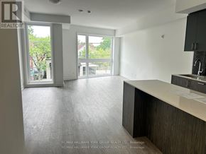 Toronto (Birchcliffe-Cliffside) townhouse for rent - A spacious, empty room with a kitchen area and a view of the outdoors through the windows.