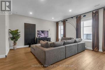 Tillsonburg townhouse for rent - A living room with a grey couch and a plant.