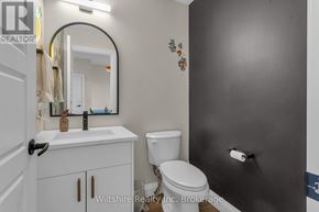 Tillsonburg townhouse for rent - A bathroom with a toilet, sink, and mirror.