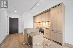 Toronto (Bayview Village) condo for rent - A modern kitchen with wooden cabinets and a black door.