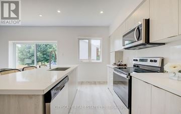 Cambridge townhouse for rent - A modern kitchen with white cabinets and appliances, a microwave above the stove, and a dining area with chairs and a table.