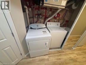 Kitchener apartment for rent - A white washer and dryer in a small room with wooden flooring.