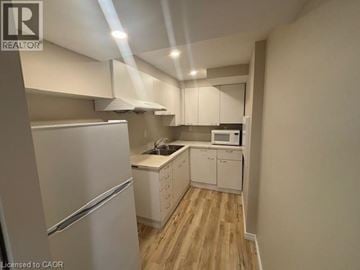 Kitchener apartment for rent - A kitchen with a refrigerator, microwave, and cabinets.