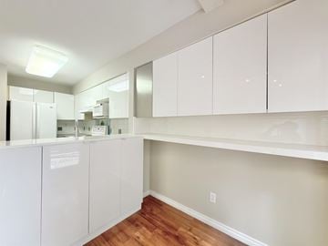 Surrey townhouse for rent - A kitchen with white cabinets and a wooden floor.