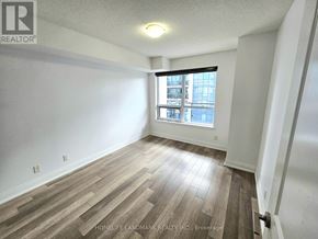 Richmond Hill (Doncrest) condo for rent - A room with wooden flooring and a window overlooking a cityscape.