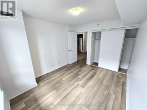Richmond Hill (Doncrest) condo for rent - A room with wooden flooring and white walls, with a doorway leading to another room.