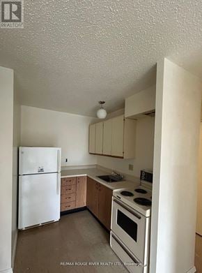 Sault Ste Marie multi-family for rent - A white refrigerator is in a kitchen with wooden cabinets.