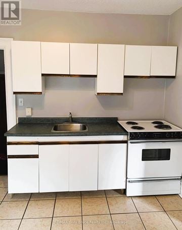 Owen Sound apartment for rent - A kitchen with white cabinets and a black counter top.