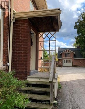 Owen Sound apartment for rent - A wooden porch with a brick wall and a white door.