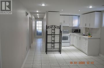 Toronto (Pleasant View) apartment for rent - A white kitchen with a black fridge and a white tiled floor.