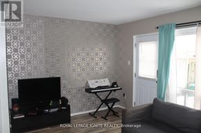Brantford townhouse for rent - A living room with a black television and a grey couch.