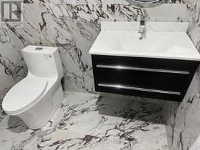 Welland (Lincoln/Crowland) apartment for rent - A white toilet sits next to a sink in a marble bathroom.