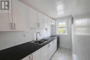 Toronto (Cabbagetown-South St. James Town) condo for rent - A kitchen with white cabinets and black countertops.