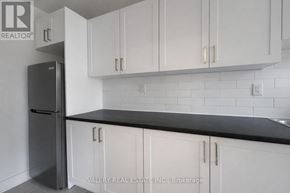 Toronto (Cabbagetown-South St. James Town) condo for rent - A kitchen with white cabinets and a black countertop.