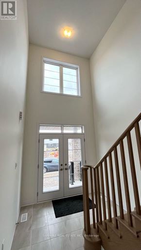 Welland (Dain City) apartment for rent - A hallway with a wooden staircase and a glass door leading to a balcony.