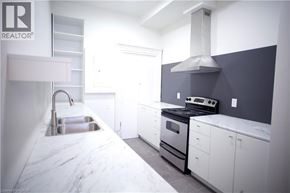 Hamilton townhouse for rent - A modern kitchen with white cabinets and a marble countertop.