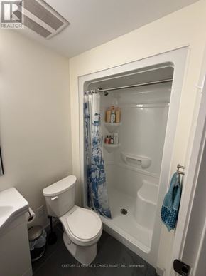 Waterloo condo for rent - A white toilet sits next to a walk-in shower in a small bathroom.