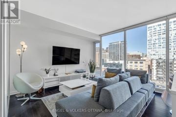 Ottawa condo for rent - A modern living room with a grey sofa and a white chair.