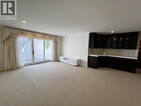 Vancouver apartment for rent - A spacious living room with a large window and a kitchen area in the background.