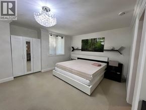 Vancouver apartment for rent - A bedroom with a large bed, a chandelier, and a painting on the wall.