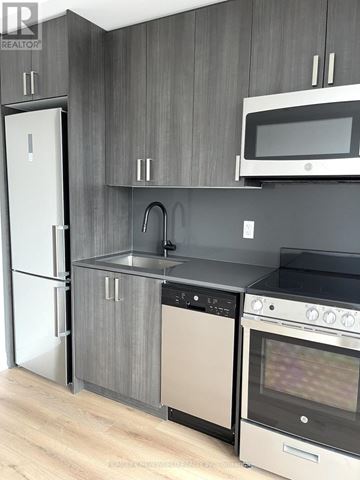 Toronto (Dovercourt-Wallace Emerson-Junction) condo for rent - A modern kitchen with a white fridge, black oven, and a microwave above the stove.